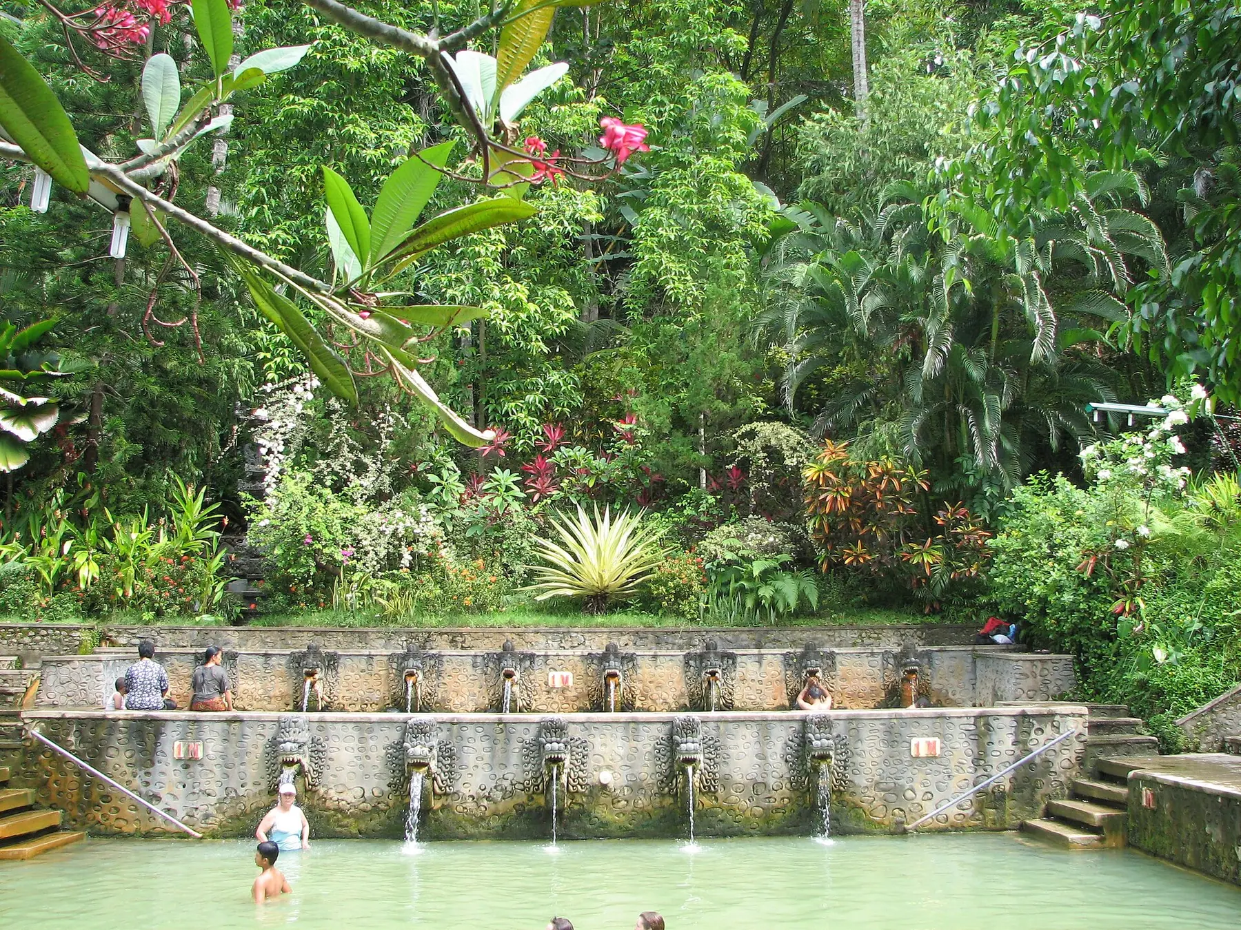 Carved naga spouts pouring sulphur water into the stone pools at Air Panas Banjar