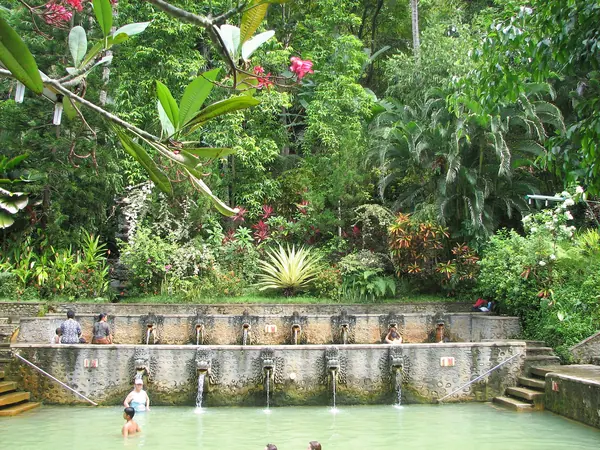 Carved naga spouts pouring sulphur water into the stone pools at Air Panas Banjar