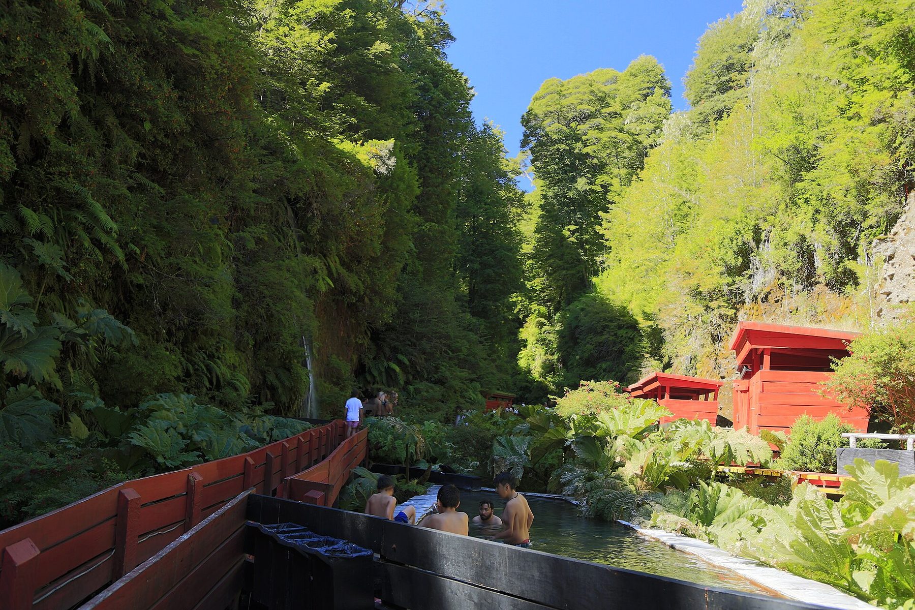 Red boardwalk and slate hot-spring pools in the ravine at Termas Geométricas